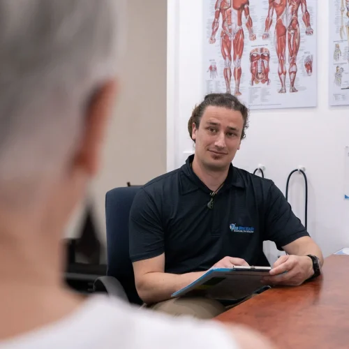 Exercise Physiologist sitting in a consult room with a patient, talking about the patient's medical history